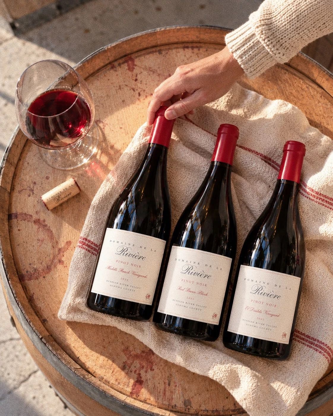 2022 Middle Reach Vineyards, 2021 Red Barn Block, and 2021 El Diablo Vineyard Pinot Noir on linen atop an oak barrel